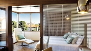 Una camera d'albergo moderna con una grande finestra, un letto con cuscini, una sedia e un tavolo.