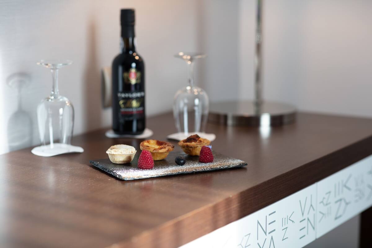 Un coin bar avec une bouteille de vin, des verres et des pâtisseries disposés sur une planche de service en ardoise.