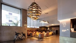 Una hall d'albergo moderna con un'ampia area salotto, una bicicletta e la reception.