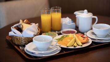 A breakfast tray with toast, fruit, juice, and tea on a wooden table.