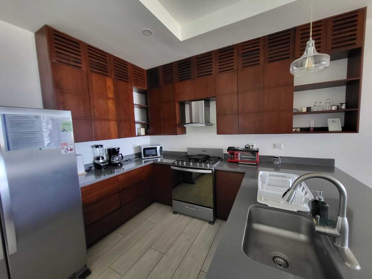 Una cocina moderna con gabinetes de madera, electrodomésticos de acero inoxidable y horno empotrado.