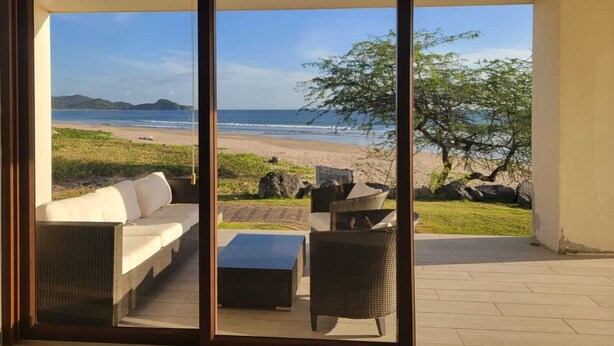A balcony with a view of the beach and ocean.