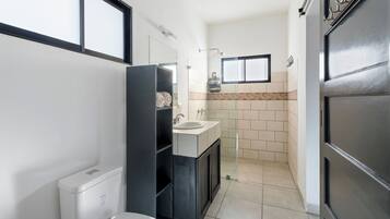 Un baño moderno con inodoro, lavabo y zona de ducha.