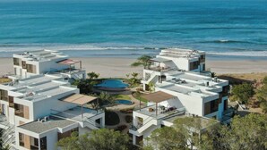A modern resort with multiple buildings, a pool area, and a beach view.