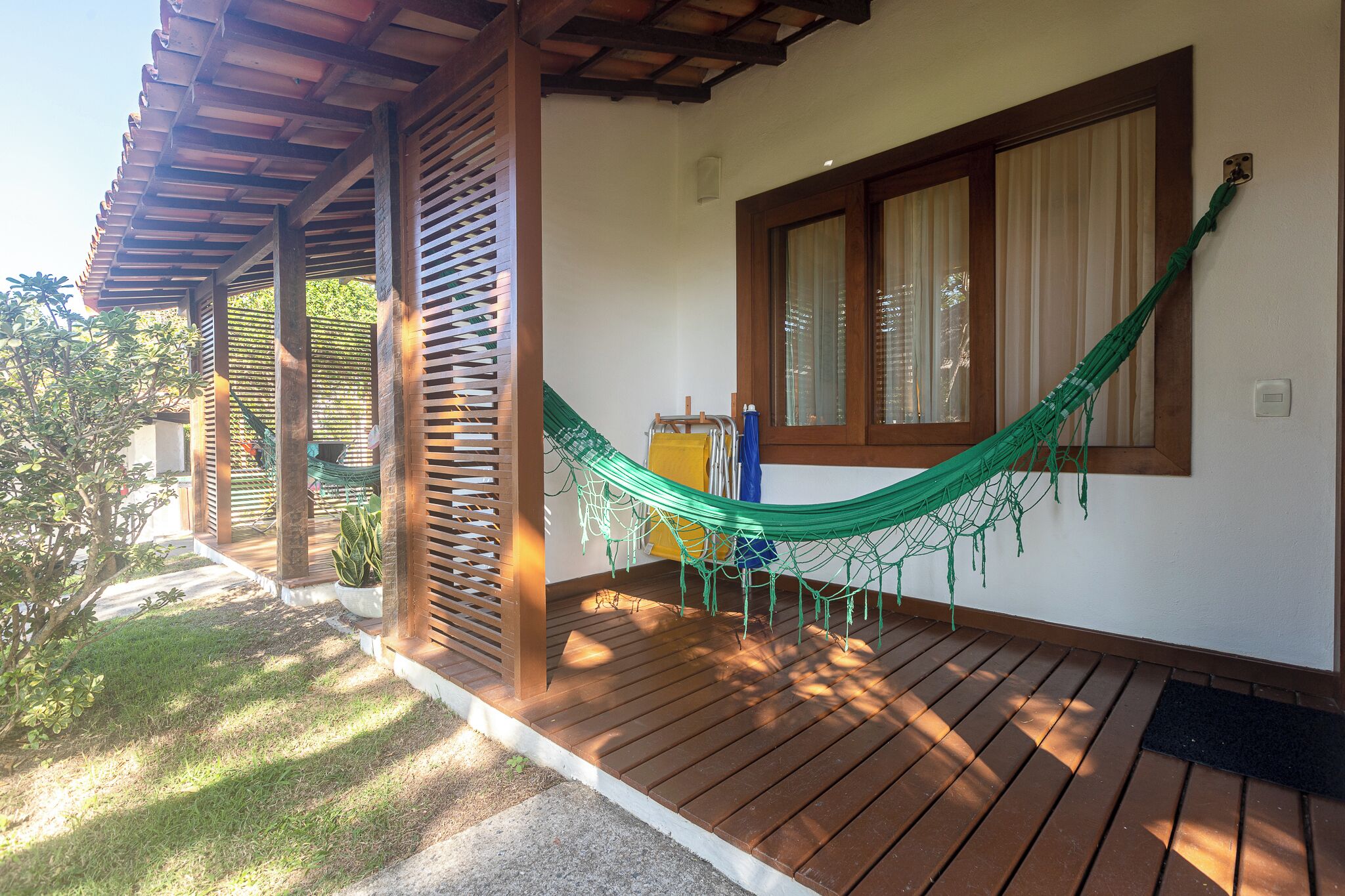 A wooden deck with a hammock, a small table, and a potted plant.