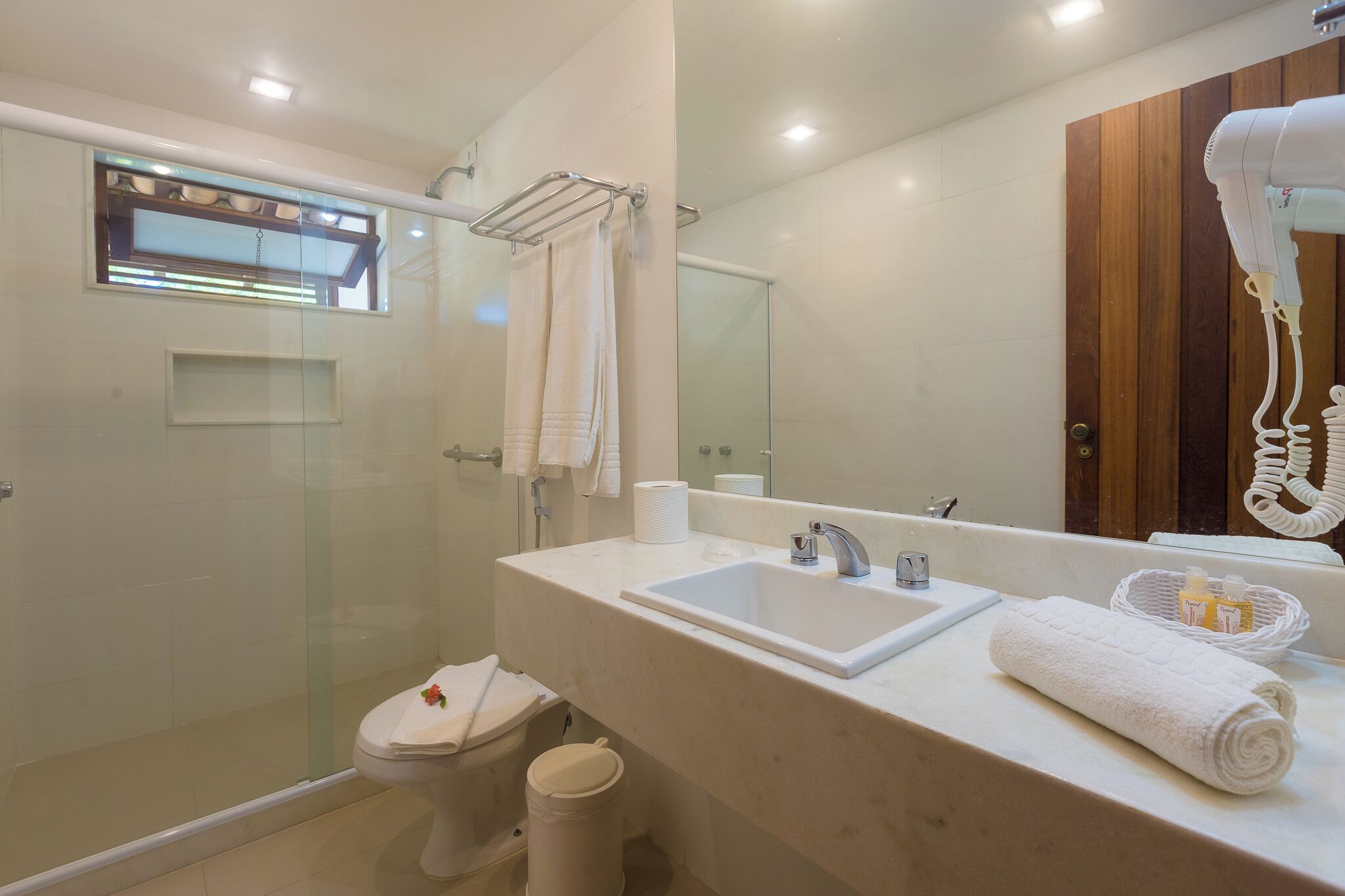 A modern bathroom with a glass-enclosed shower, a white sink, and a large mirror.