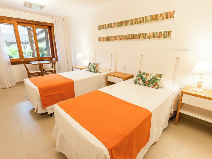 Habitación de hotel con dos camas, una mesita y una ventana con cortinas.