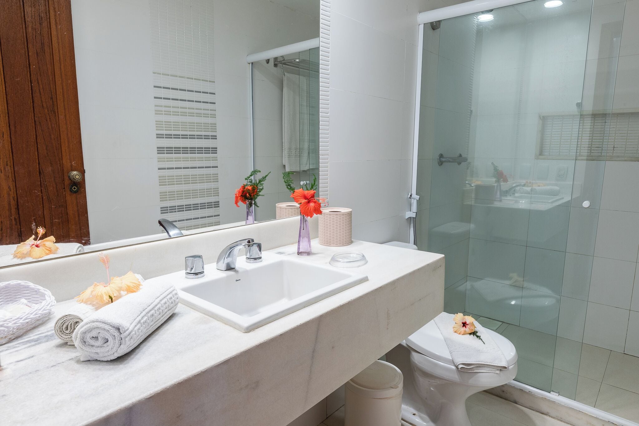 Un baño con lavamanos blanco, espejo y cabina de ducha de vidrio.