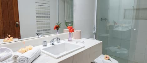 Un baño con lavamanos blanco, espejo y cabina de ducha de vidrio.