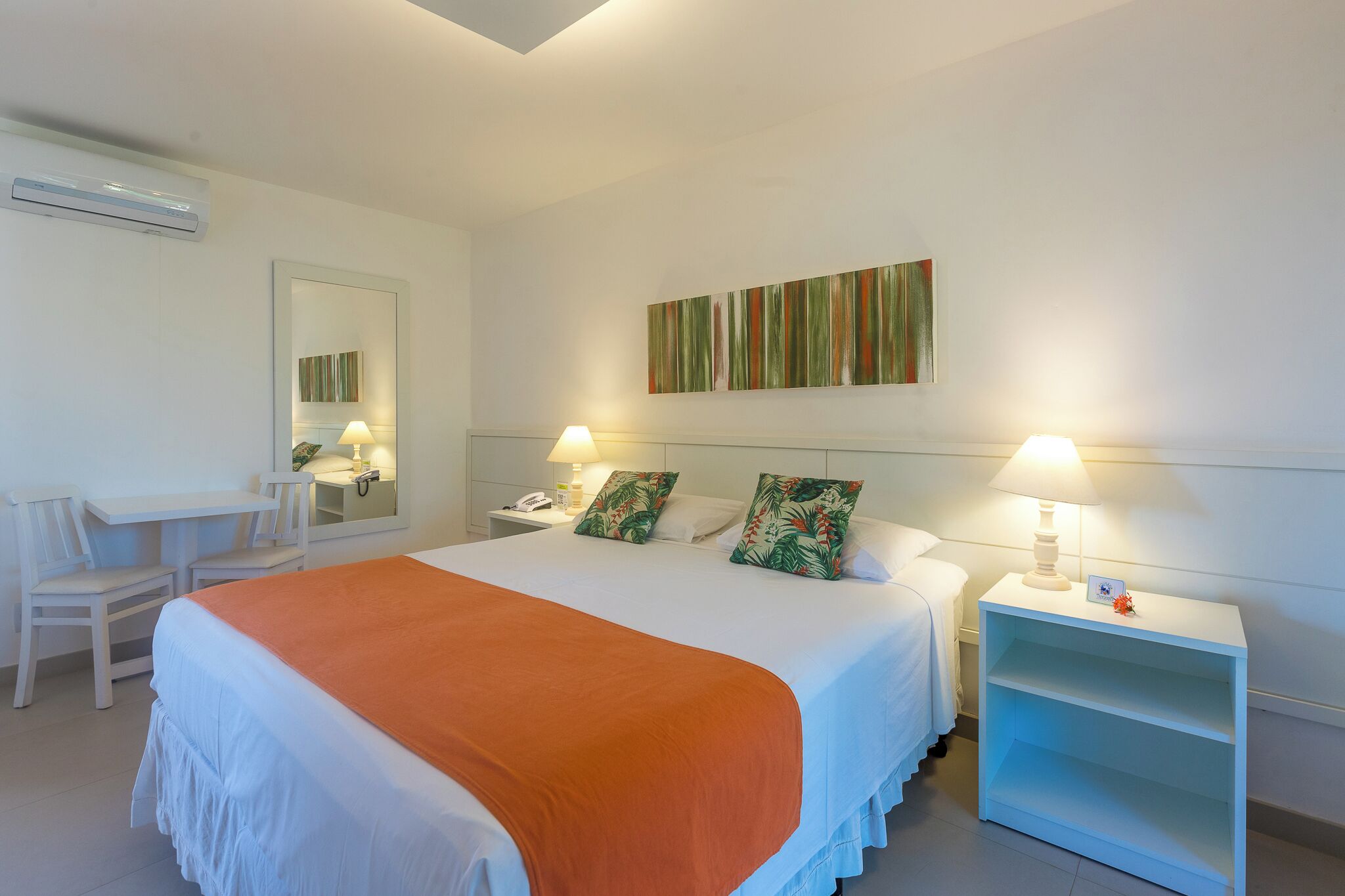 Une chambre d’hôtel comprenant un lit, deux tables de chevet, un bureau et des chaises.