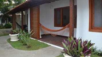 Una casa con porche, una hamaca y plantas en macetas.