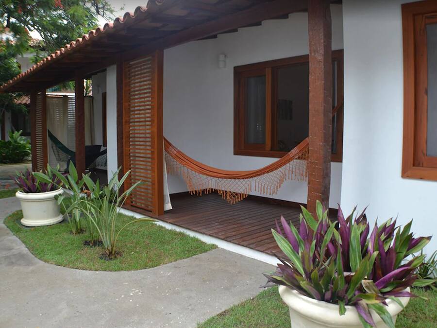 Una casa con porche, una hamaca y plantas en macetas.