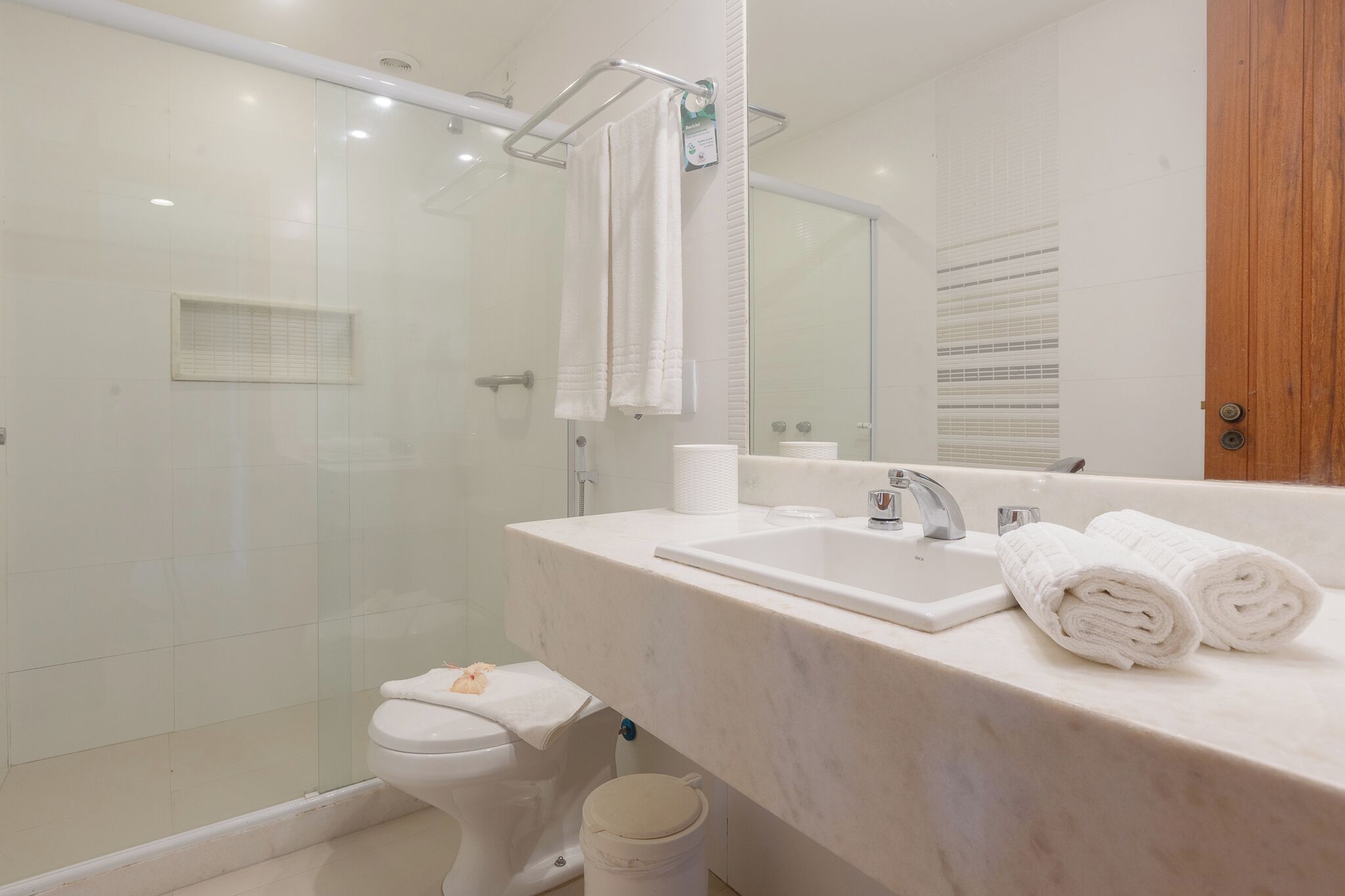A modern bathroom with a glass-enclosed shower, a white sink, and a large mirror.