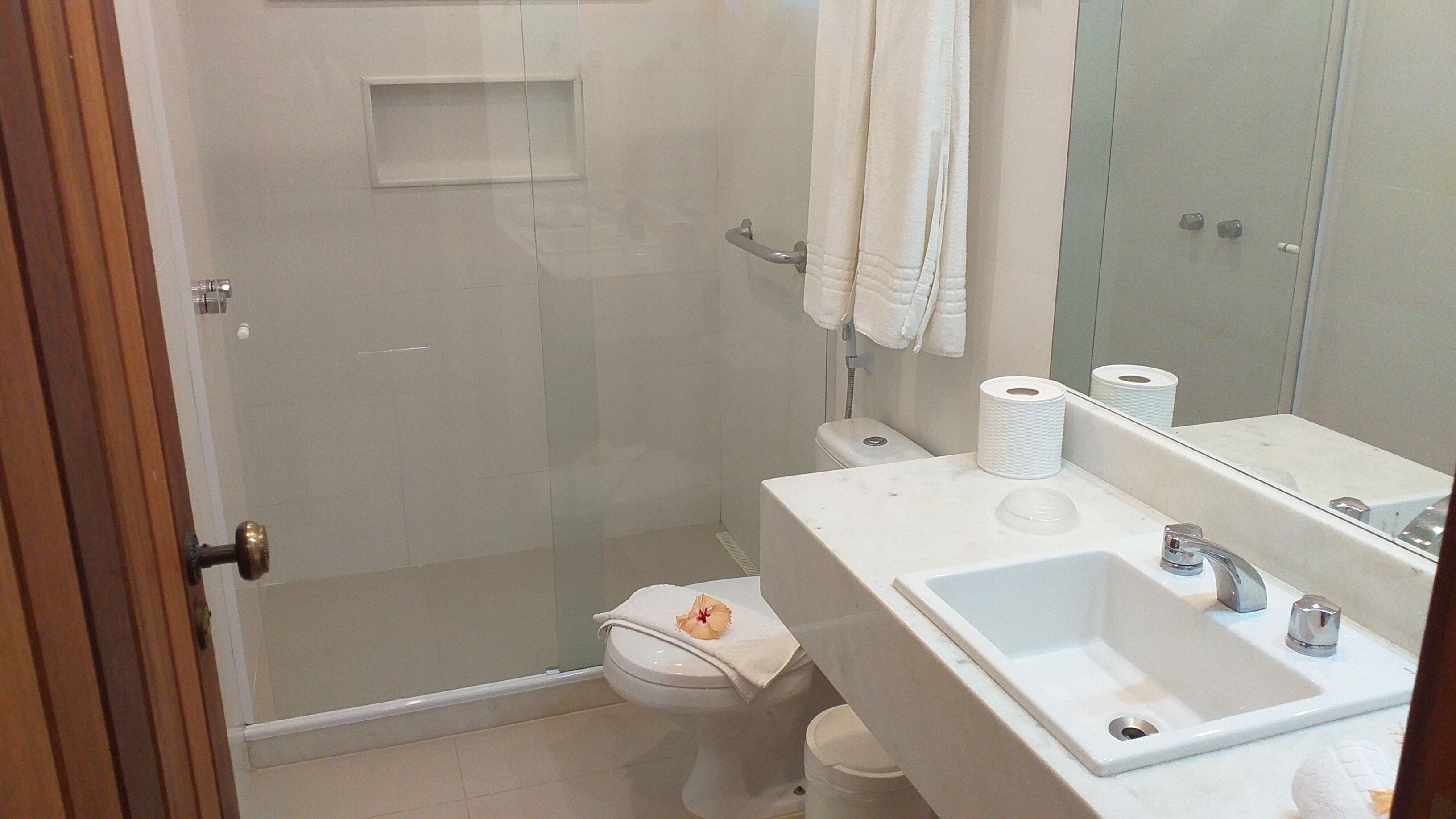 Un baño con ducha de vidrio, inodoro, lavamanos y espejo.
