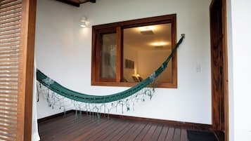 A wooden deck with a hammock, a window with a view, and a door.