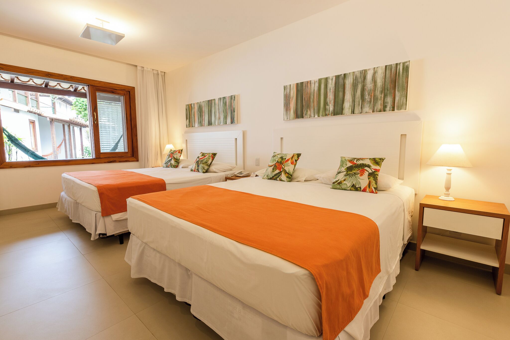 Una habitación de hotel con dos camas, una ventana con cortinas y una mesita de noche con lámpara.