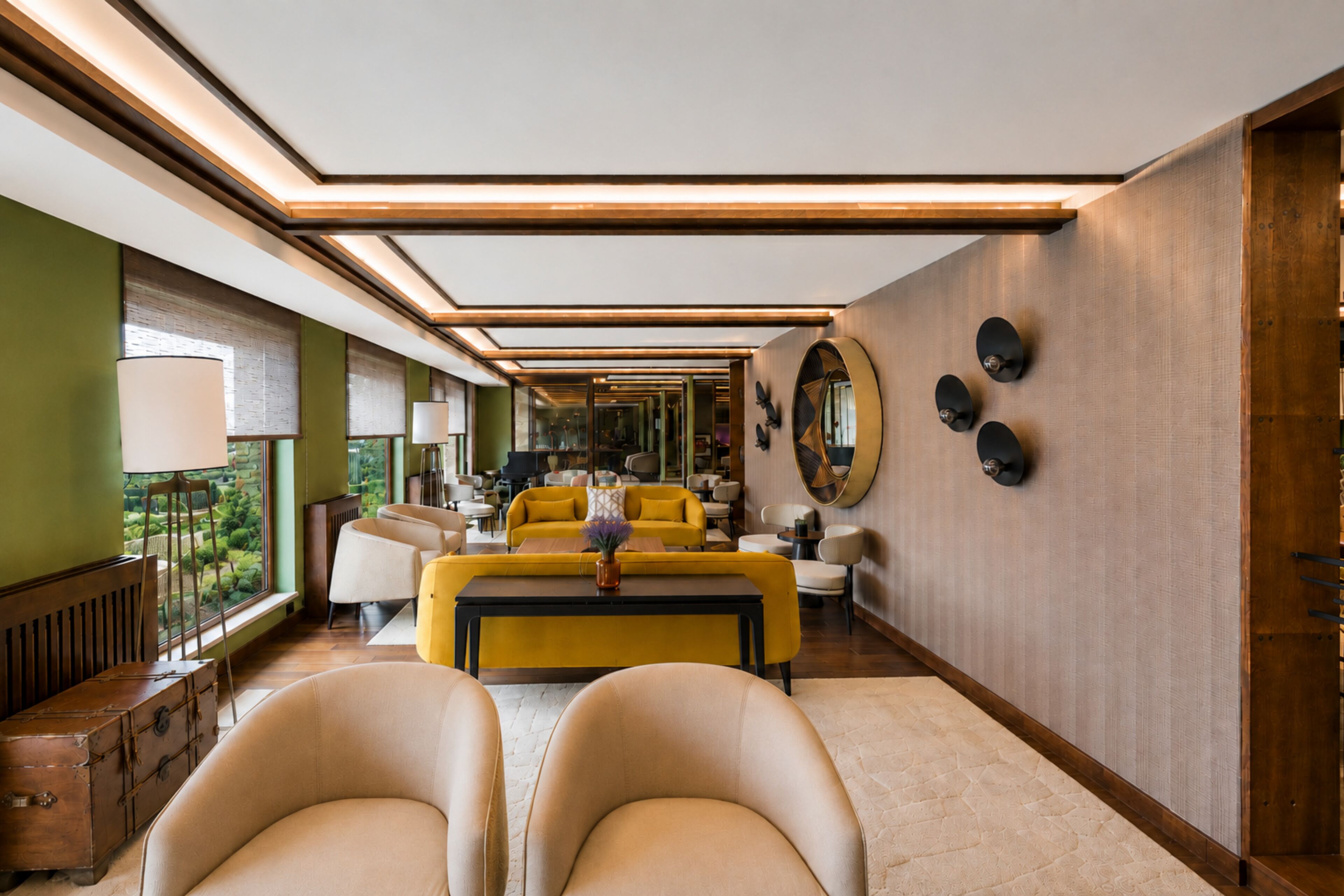 Un interior moderno con una zona de estar central, un espejo grande y vistas a un jardín a través de las ventanas.