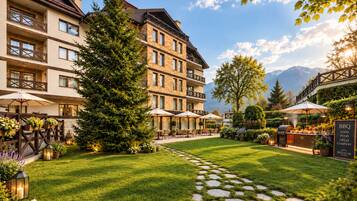 A hotel courtyard with a stone pathway, outdoor seating, and a BBQ area.