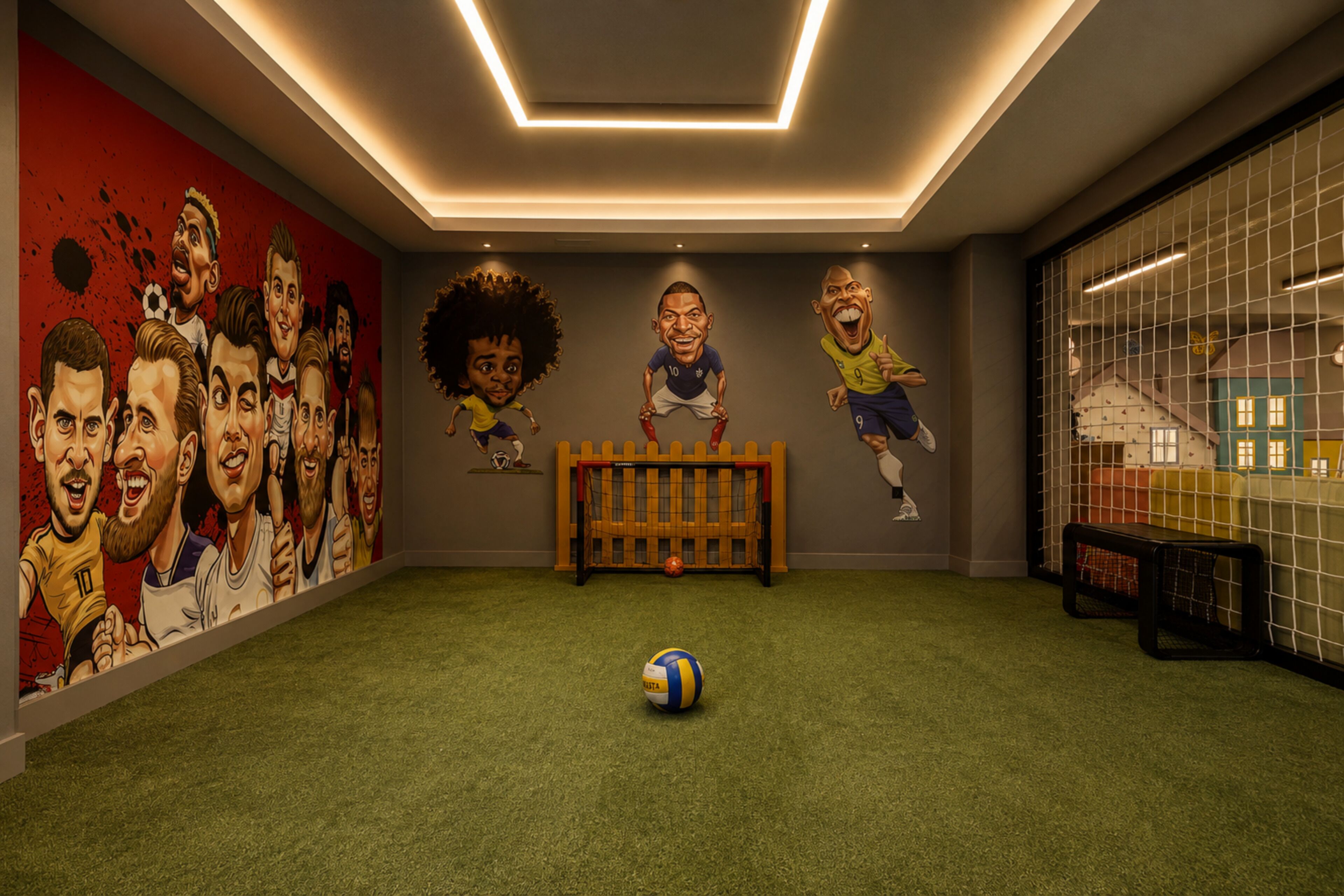 A room with a soccer-themed mural, a goalpost, and a soccer ball on artificial turf.