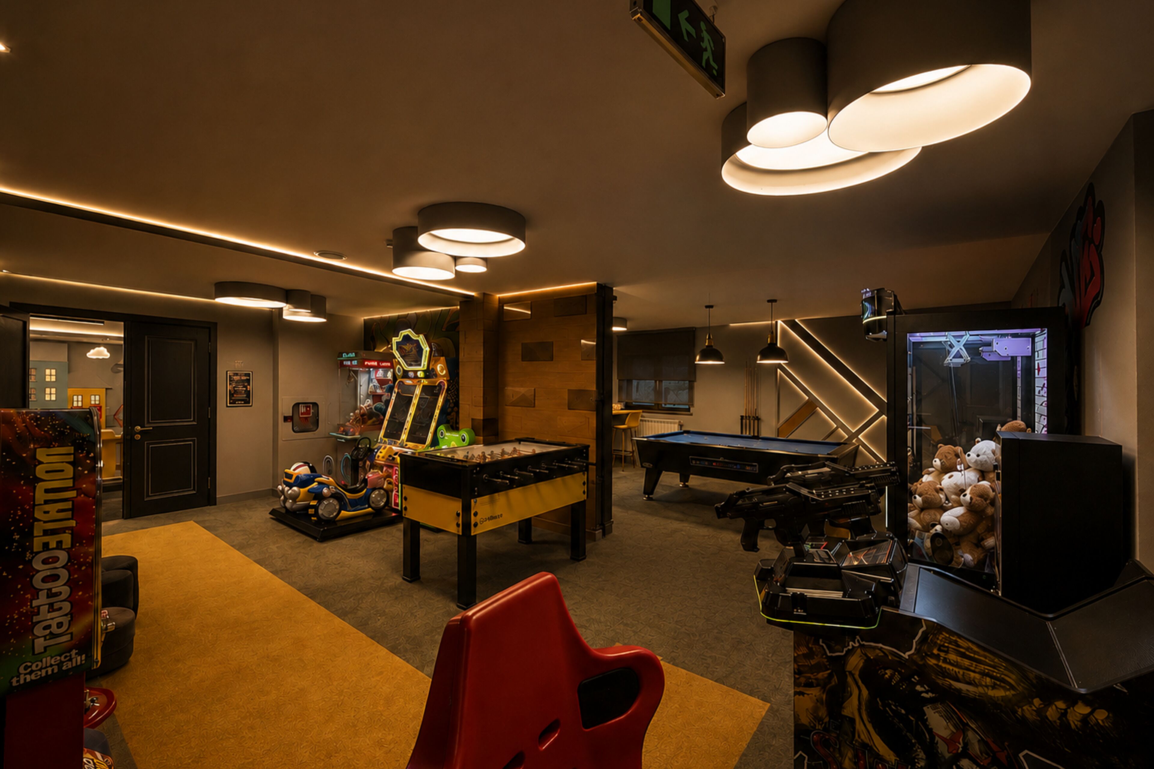 A room with a pool table, foosball table, and arcade games.