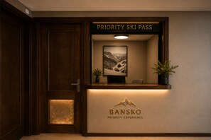 Un mostrador de recepción con un cartel que dice 'Priority Ski Pass' arriba y otro cartel que dice 'BANSKO Priority Experience' debajo.