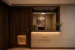Un mostrador de recepción con un cartel que dice 'Priority Ski Pass' arriba y otro cartel que dice 'BANSKO Priority Experience' debajo.