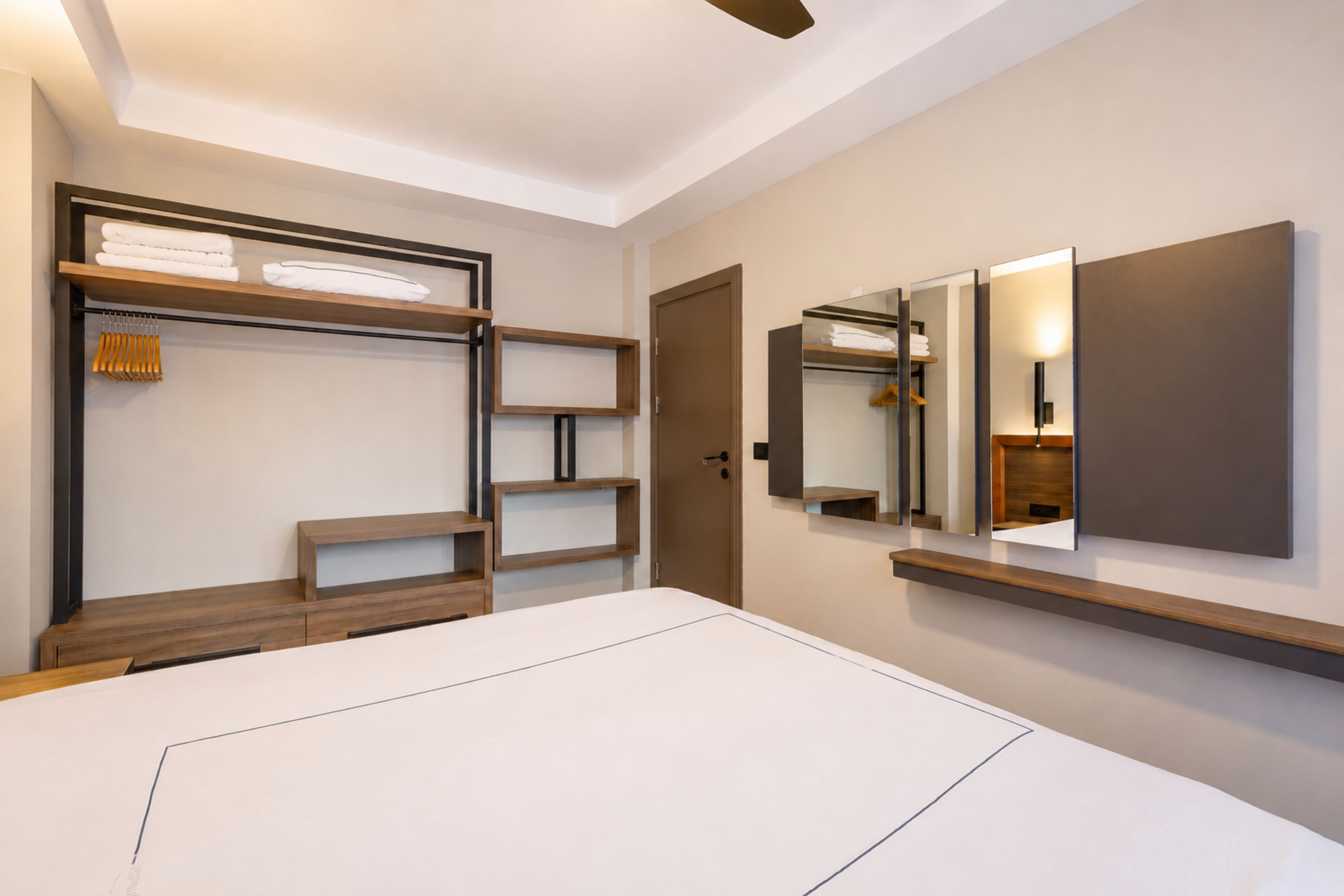 Een hotelkamer met een bed, een inbouwkast en een grote spiegel.