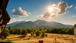 Vista de un paisaje montañoso con cielo despejado y el sol brillando entre las nubes.