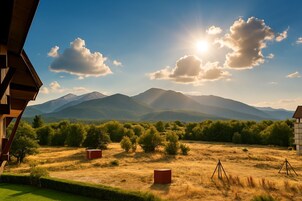 Vista de un paisaje montañoso con cielo despejado y el sol brillando entre las nubes.