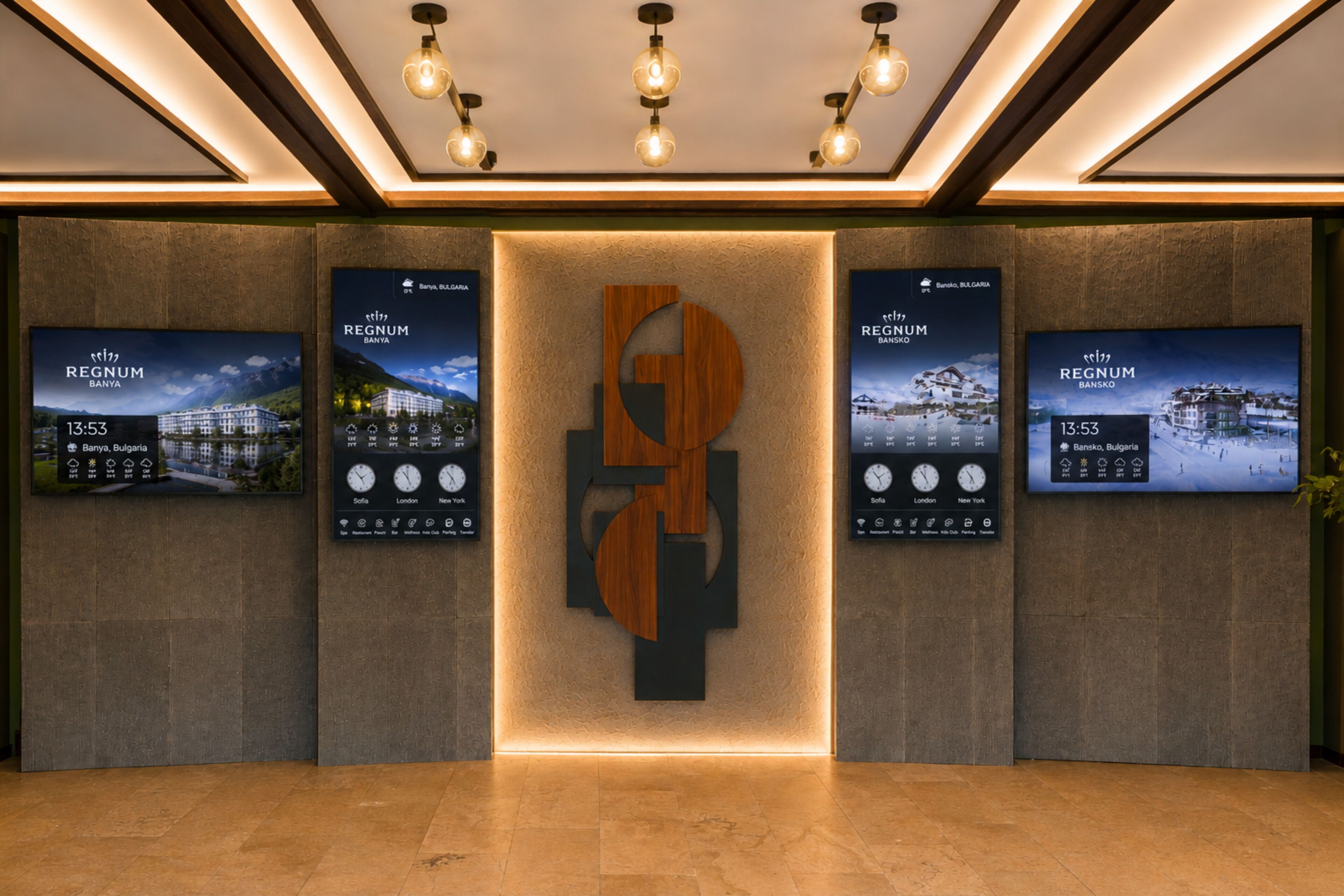Een receptiegedeelte met een centraal logo en drie digitale schermen die informatie over het hotel tonen.