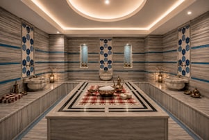 Un baño lujoso con un lavamanos central de mármol, dos bidés empotrados y una alfombra decorativa.