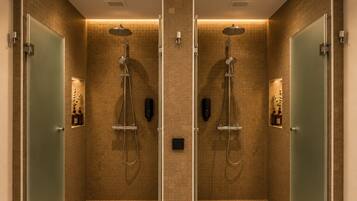 A mirrored bathroom with two shower stalls, each equipped with a handheld showerhead and a handheld massager.