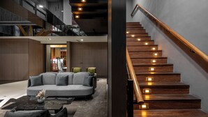 Un interior moderno con una escalera, un sofá modular y una mesa de centro.