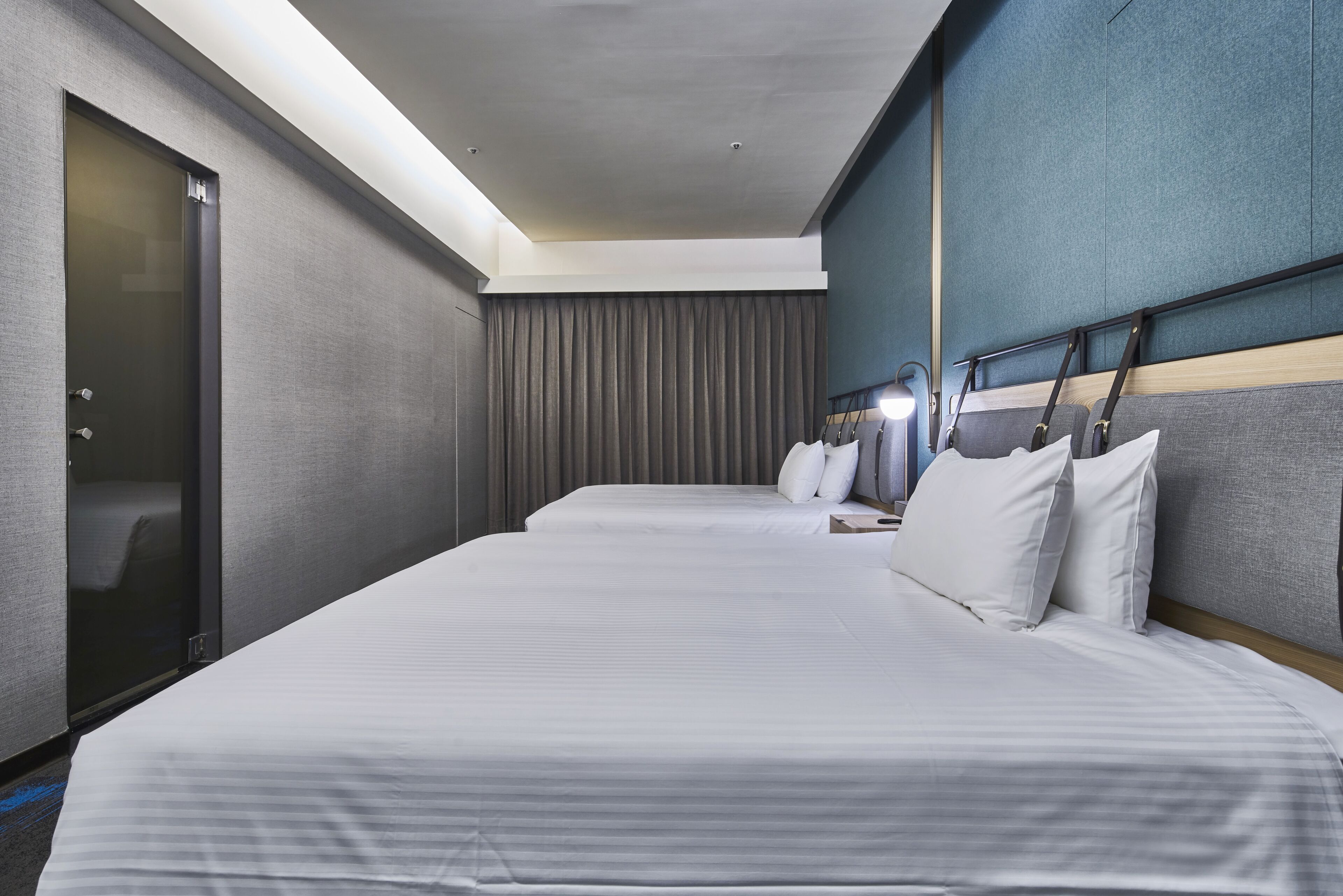 Ein Hotelzimmer mit zwei Betten, einer Schiebetür und einem großen Fenster mit Vorhängen.