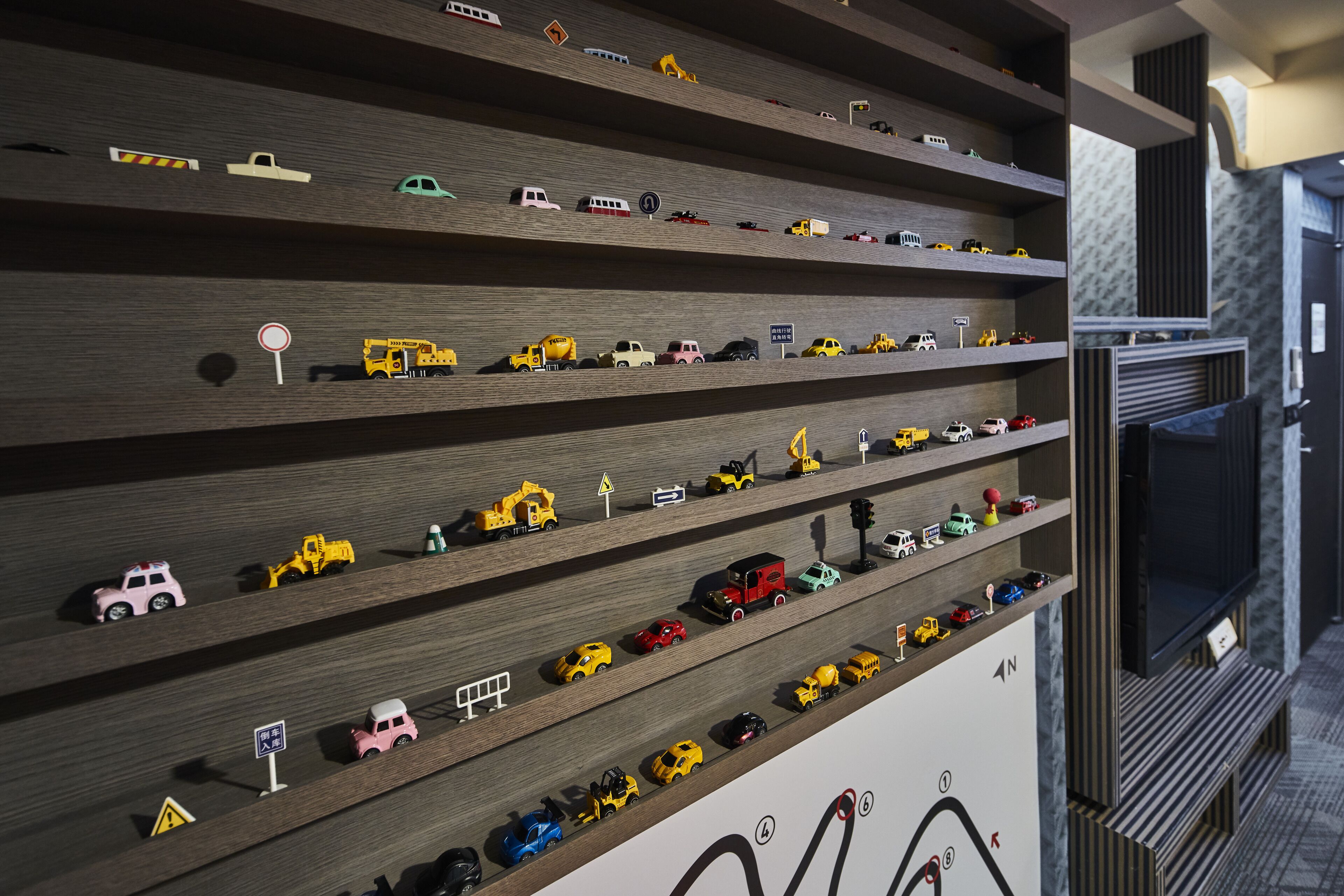 Un mur doté de plusieurs étagères où sont exposés différents véhicules miniatures.
