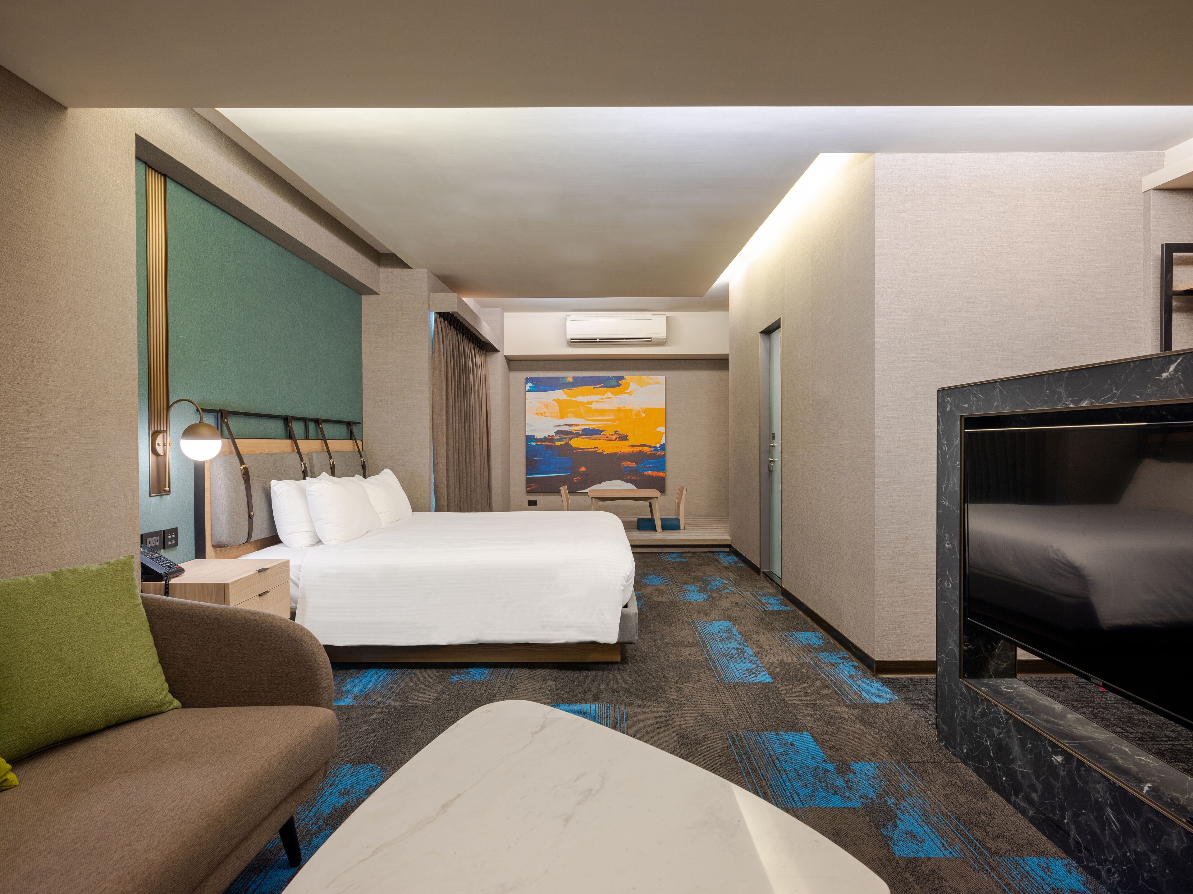 Une chambre d’hôtel avec un lit, un canapé, une télévision et un tableau au mur.