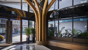 Un lobby moderno con un diseño geométrico en el techo, ventanas amplias y un suelo reflectante.