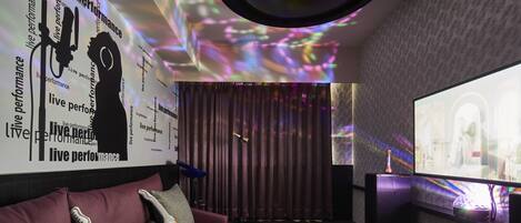 A modern living room with a large screen, a couch with a guitar, and a wall with 'live performance' text.