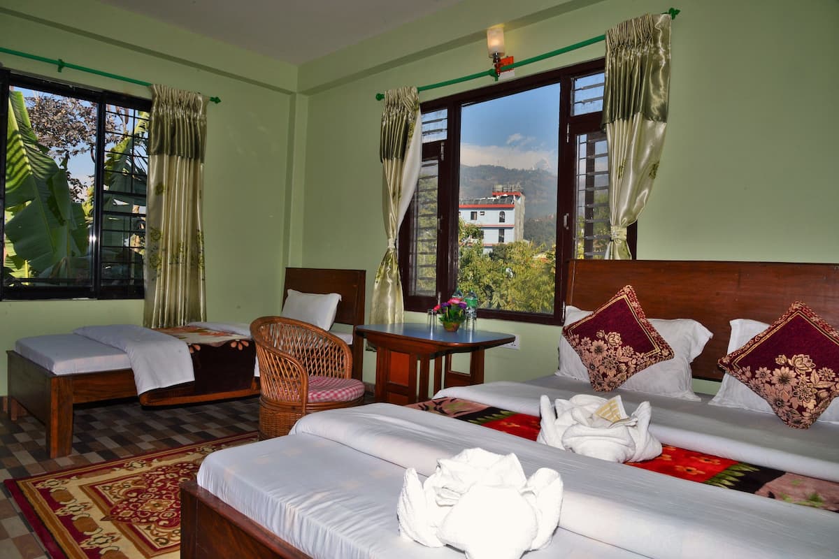 A hotel room with two single beds, a sofa bed, a dining table, and a chair.