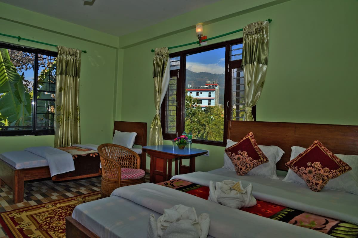 A hotel room with two beds, a sitting area, and a view of a mountain and buildings.