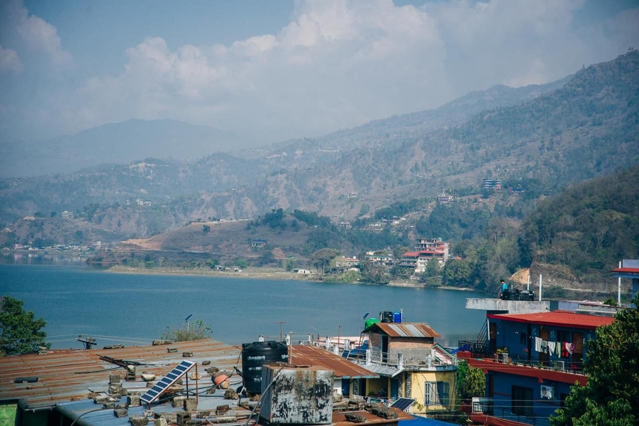 A coastal town with buildings near a body of water, surrounded by hills.