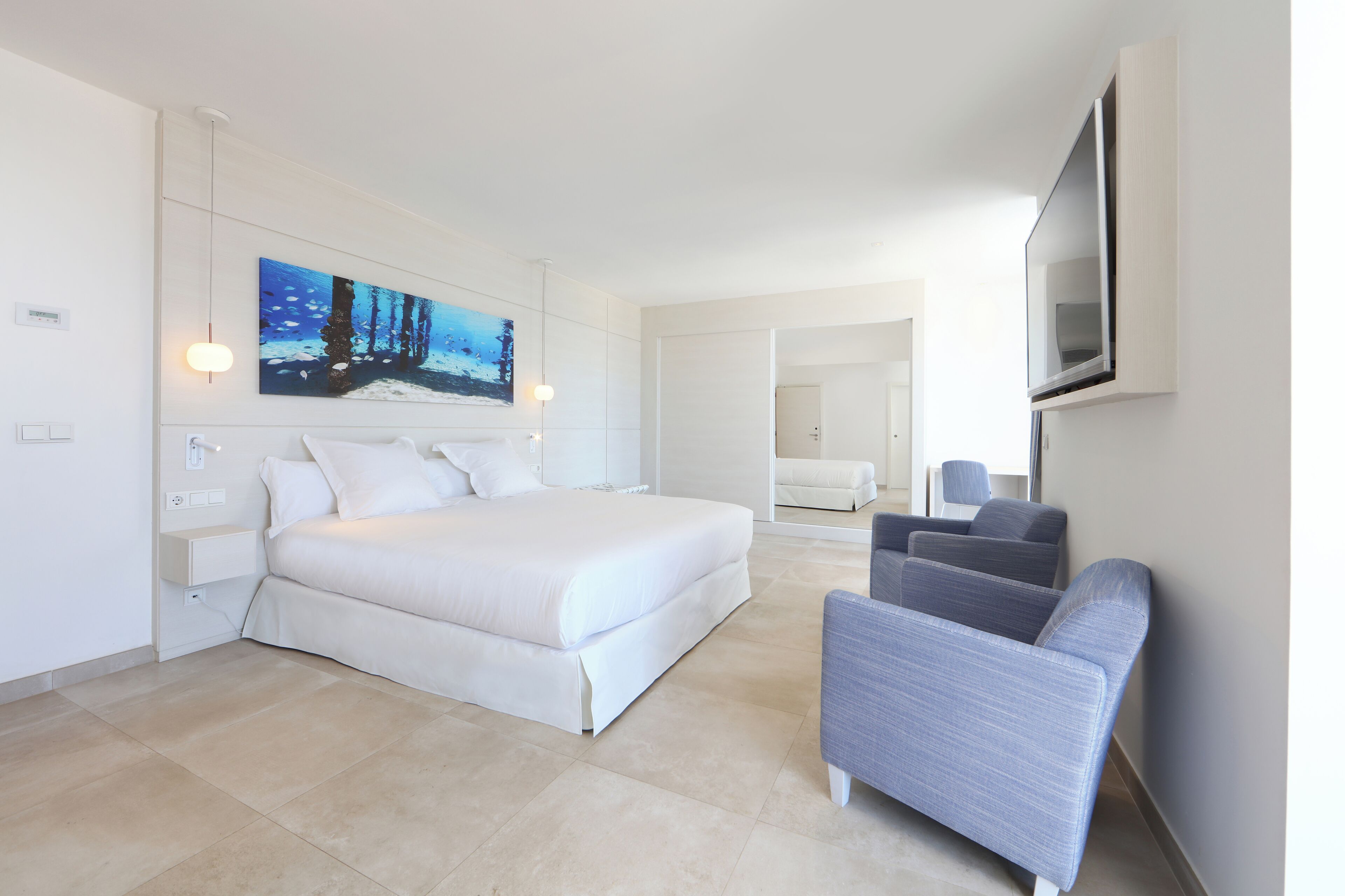 A modern hotel room with a large bed, a seating area, and a painting on the wall.