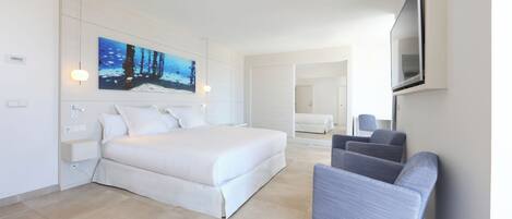 A modern hotel room with a large bed, a seating area, and a painting on the wall.