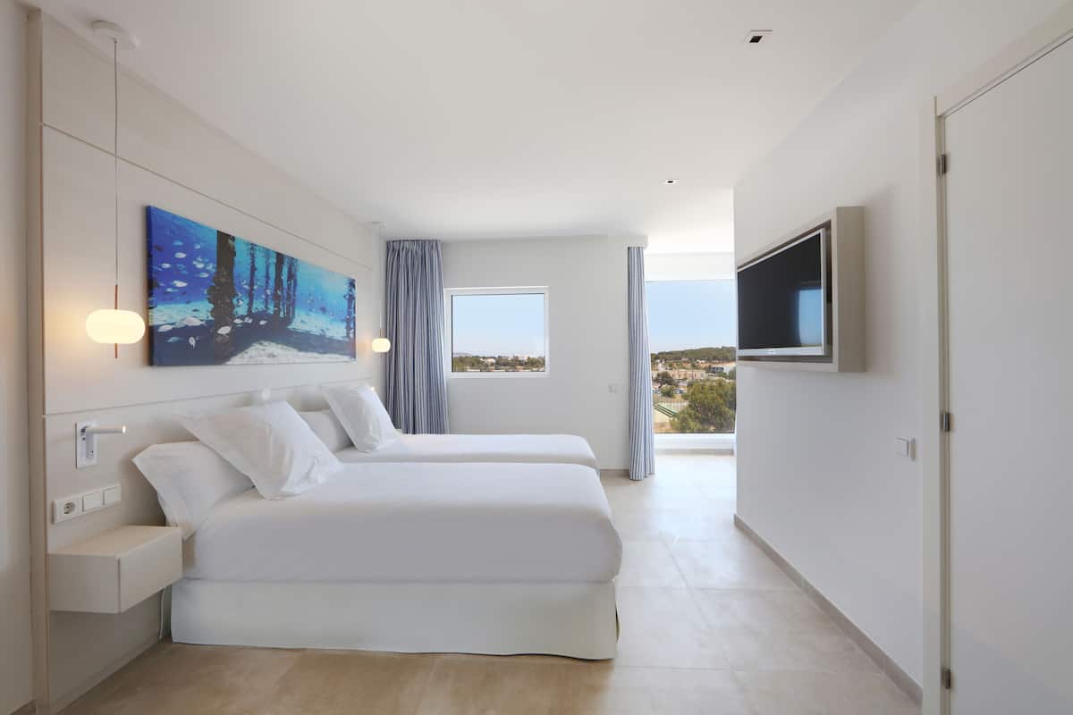 A modern hotel room with two beds, a large window, a painting, and a TV.