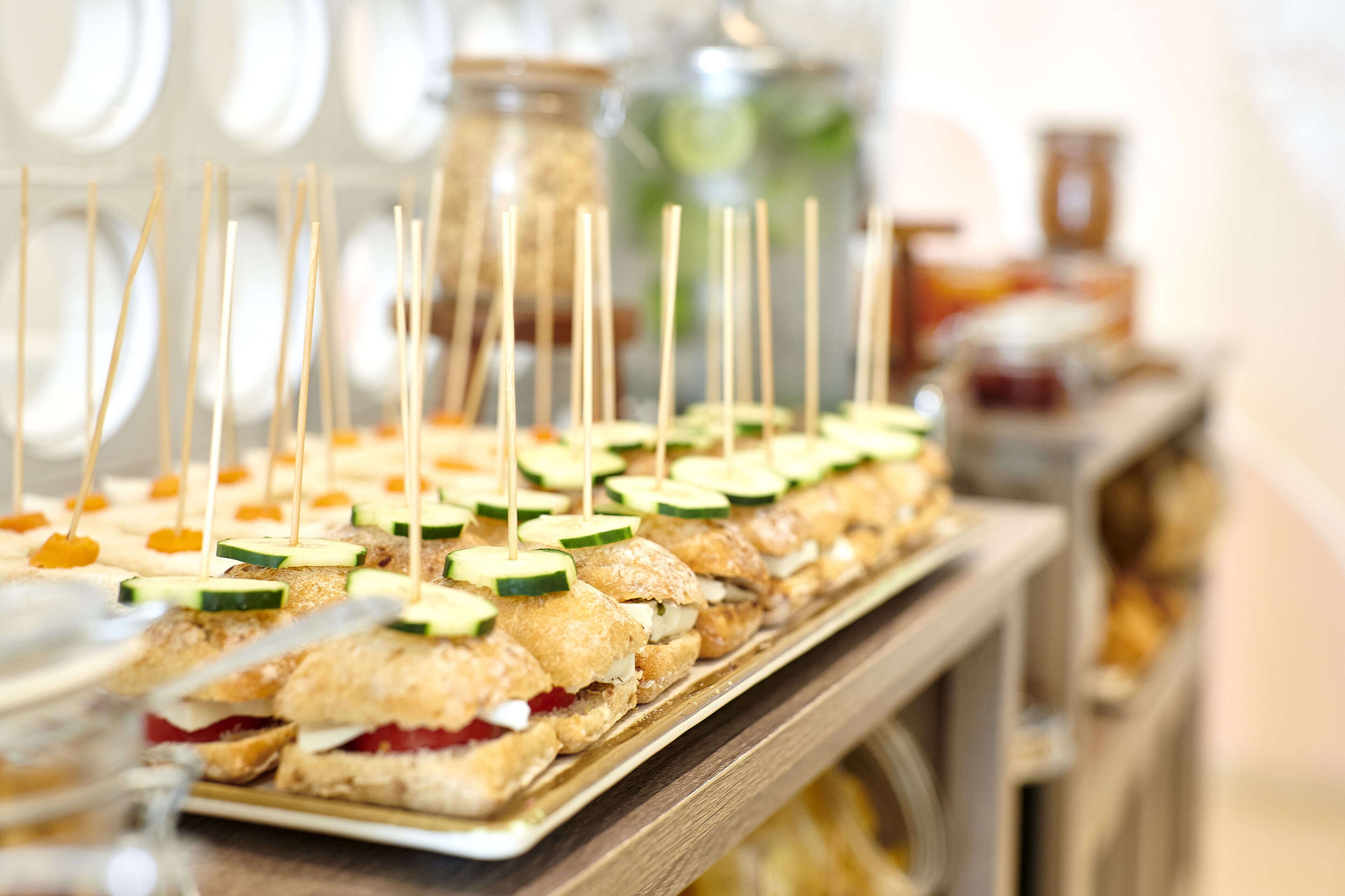 A buffet with sandwiches and fruit skewers.