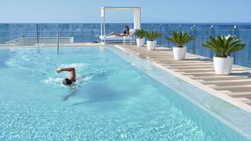 A pool area with a person swimming, a lounging area with a canopy, and potted plants.