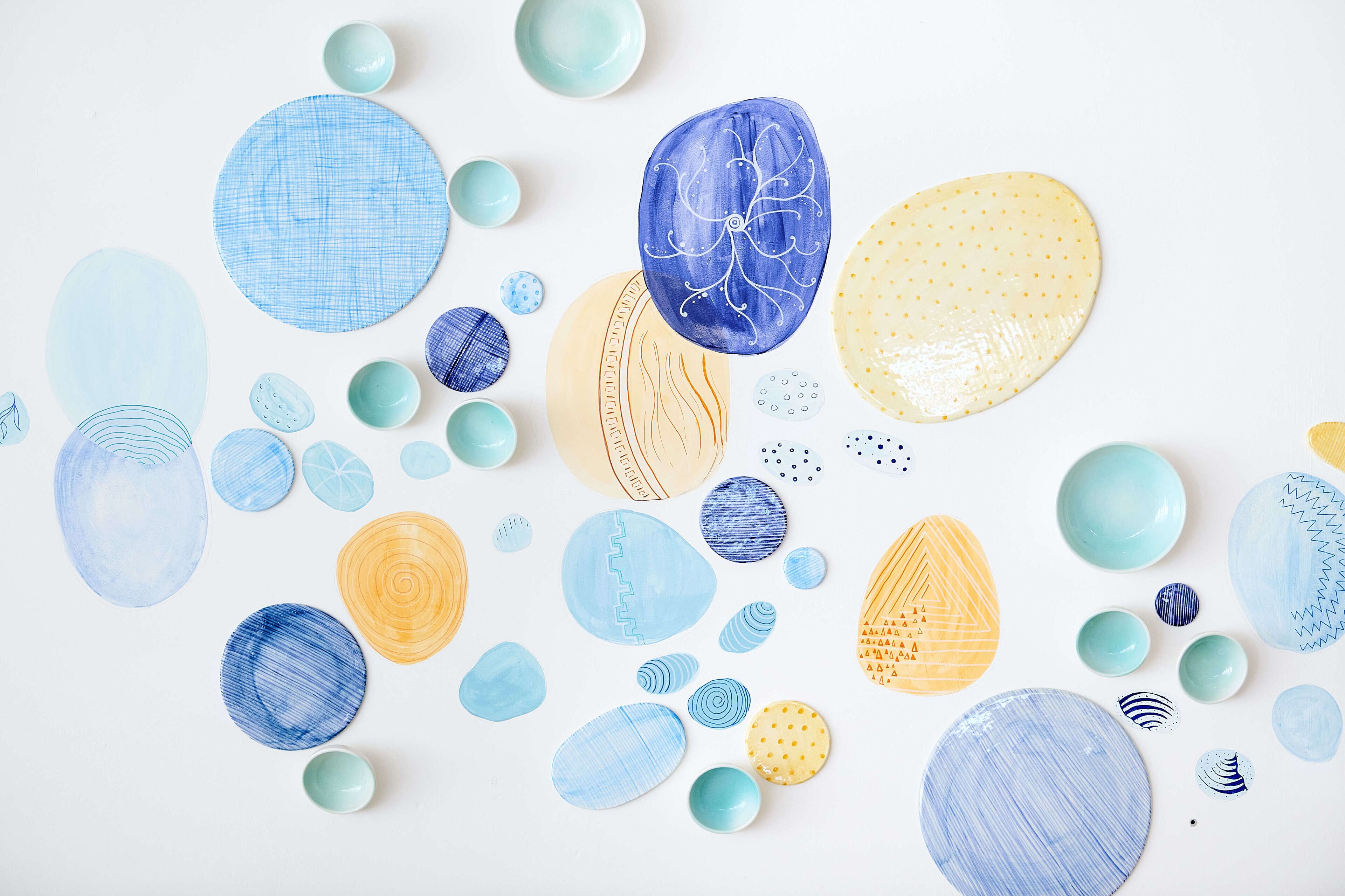Une collection d’assiettes et de bols en céramique, de différentes formes et couleurs, disposés sur une surface blanche.
