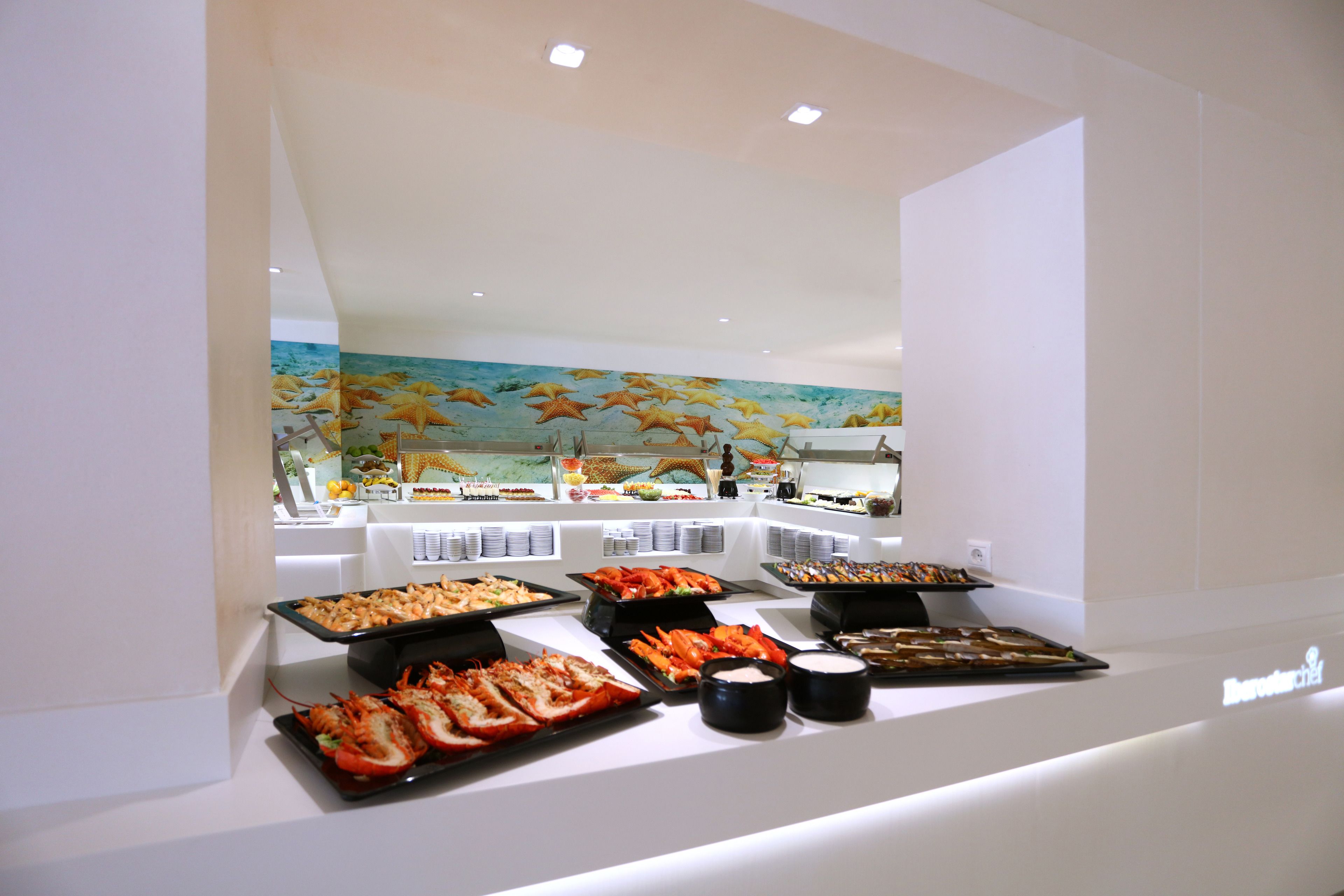 A buffet with seafood options and a mural of fish on the wall.