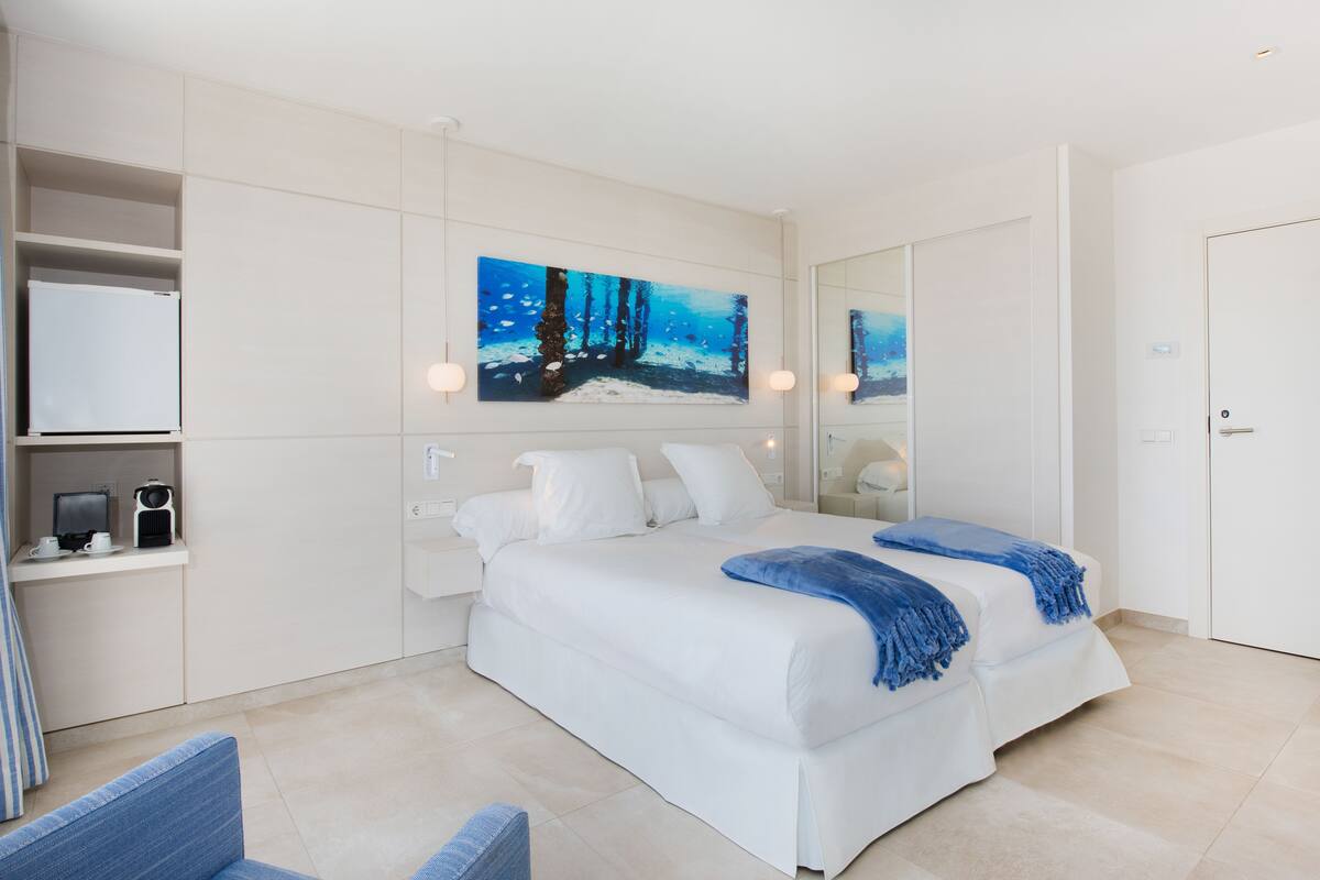 A modern bedroom with a large bed, a bedside table, a chair, and a painting on the wall.