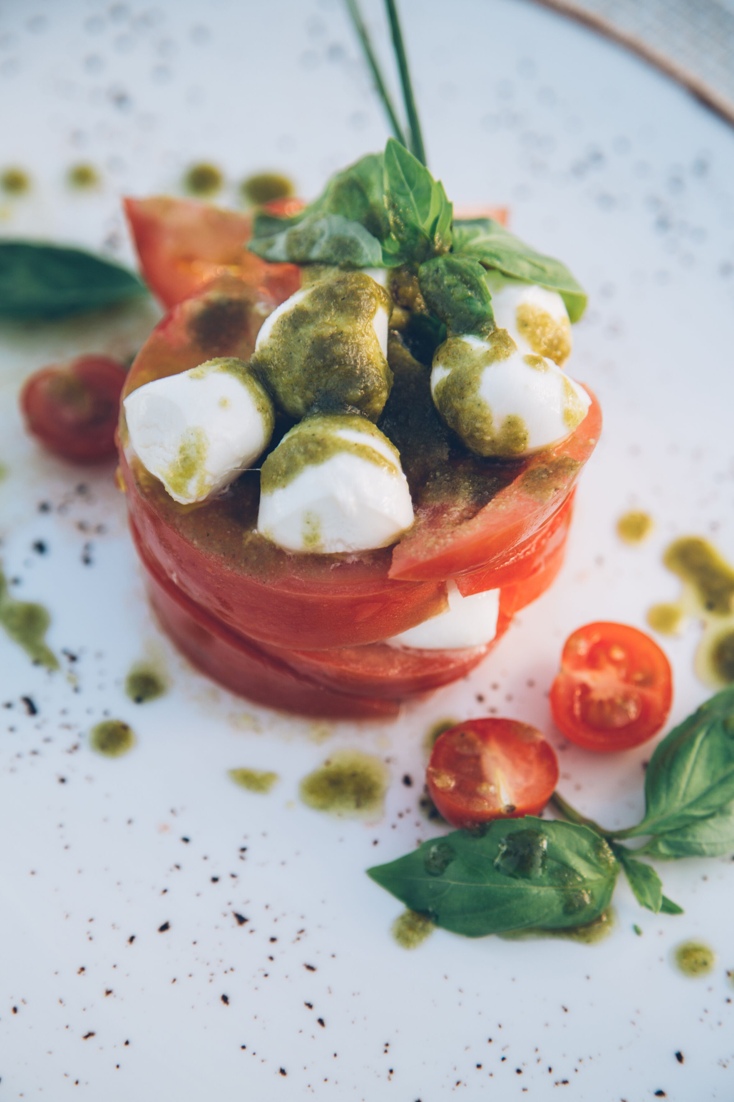 A dish with tomato slices, mozzarella balls, and basil leaves.